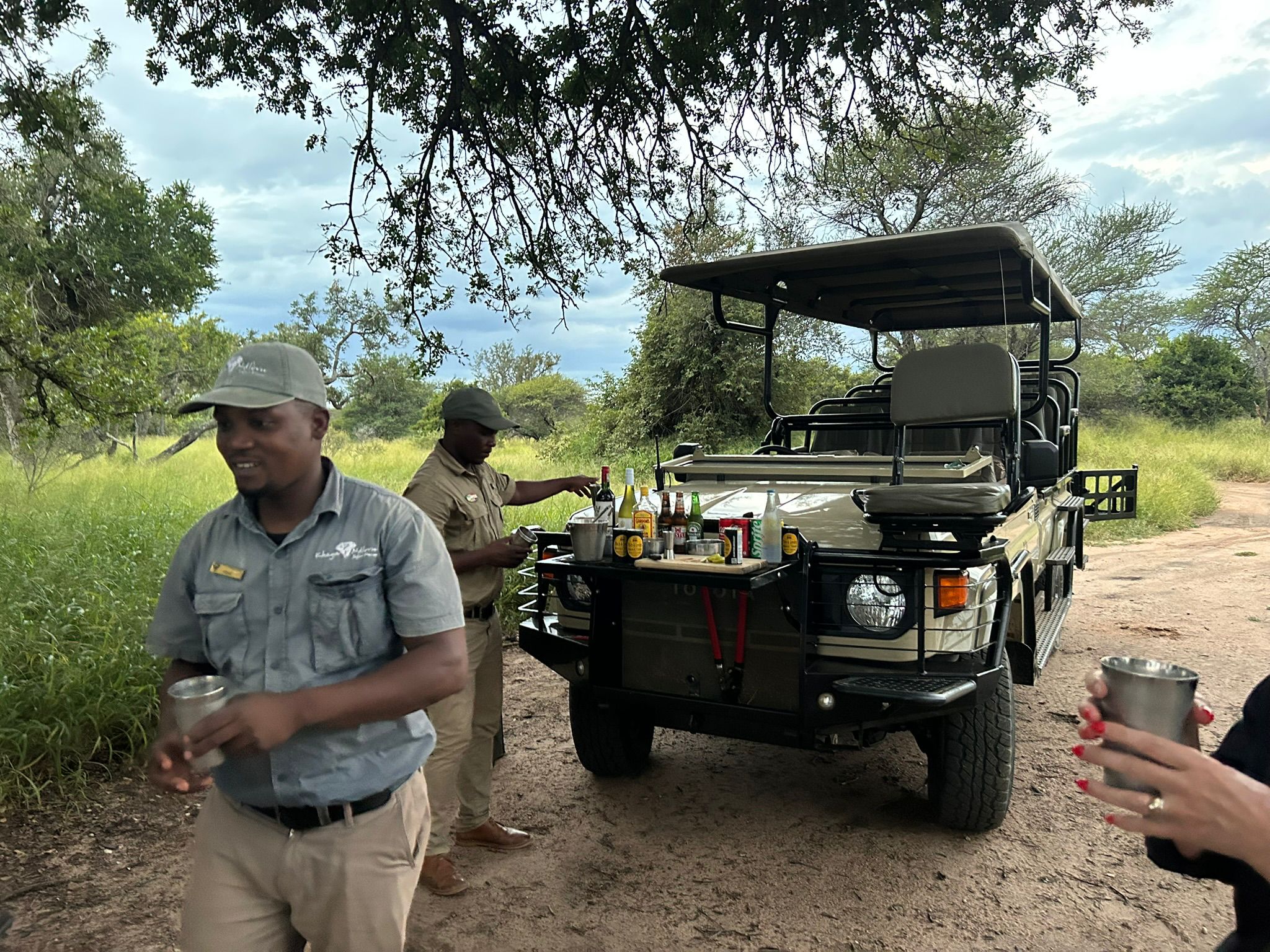 Two safari guides pouring drinks.